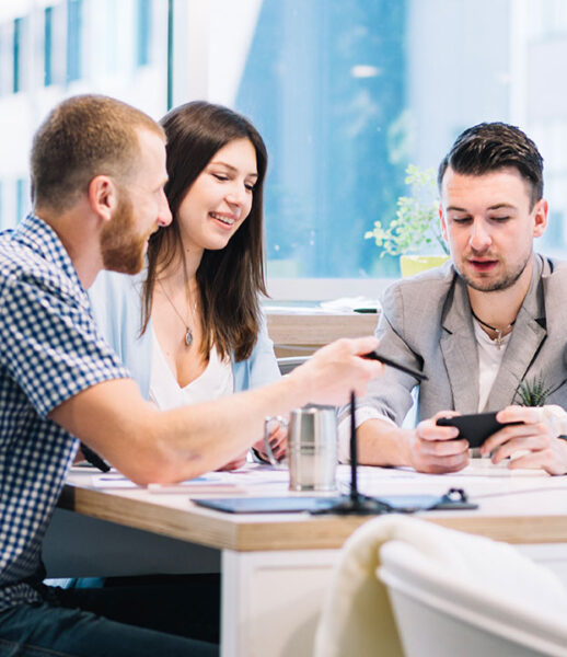 Three colleagues discussing work at a bright office table. Three colleagues discussing work at a bright office table.