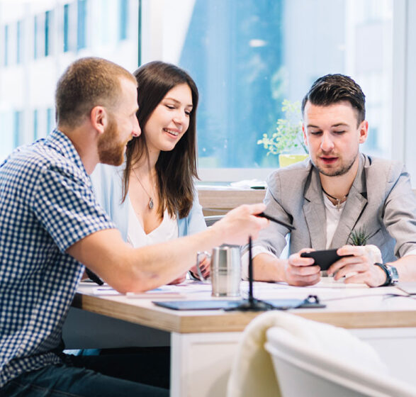Three colleagues discussing work at a bright office table. Three colleagues discussing work at a bright office table.