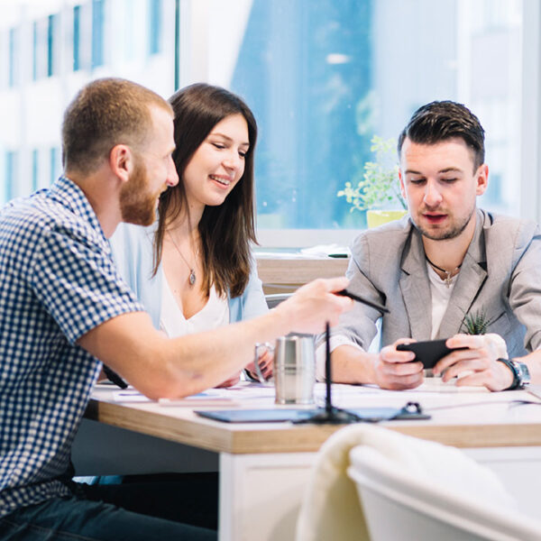 Three colleagues discussing work at a bright office table. Three colleagues discussing work at a bright office table.