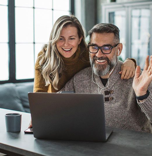 A happy couple video chatting on a laptop in a cozy room.